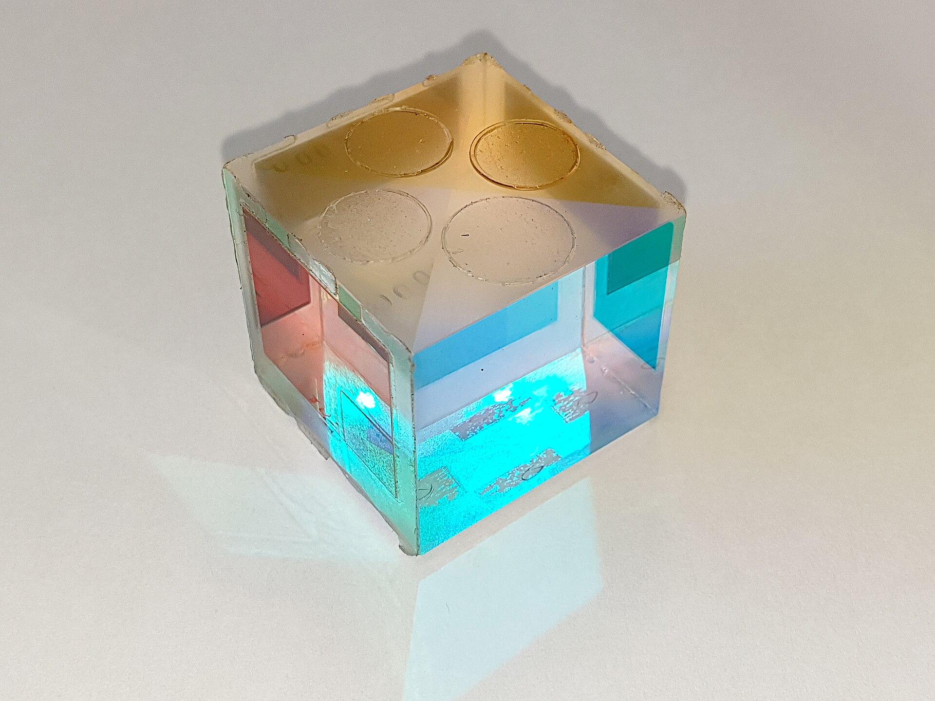 Dichroic glass cube splitting light into cyan and gold
